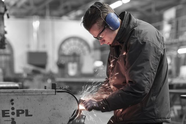 Luca werkt aan de schuurband in het staalatelier van Exclusive Steel in Made.