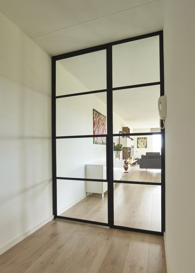 Stalen deur met glas en Paumelle scharnieren en zijpaneel in appartement in Teteringen.