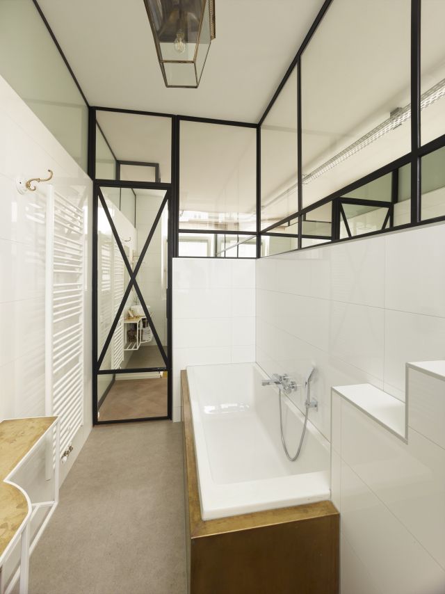 Badkamer afgescheiden door stalen pui met spiegels voor de privacy.