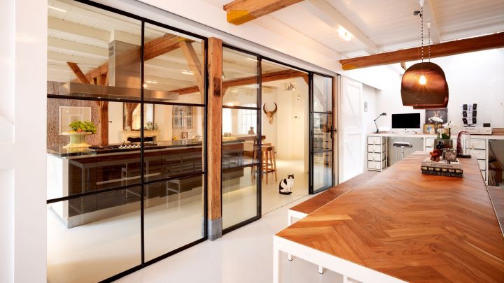 Stalen wand met glas scheidt op een transparante manier woonruimte met thuiskantoor in Voorburg.