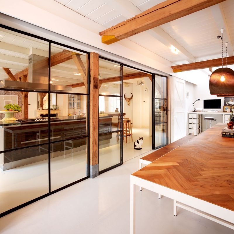 Stalen wand met glas scheidt op een transparante manier woonruimte met thuiskantoor in Voorburg.