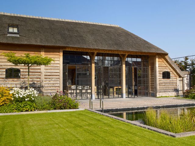 Stalen deuren in landelijke vakverdeling in een eikenhouten bijgebouw met rieten dak in Werkhoven.